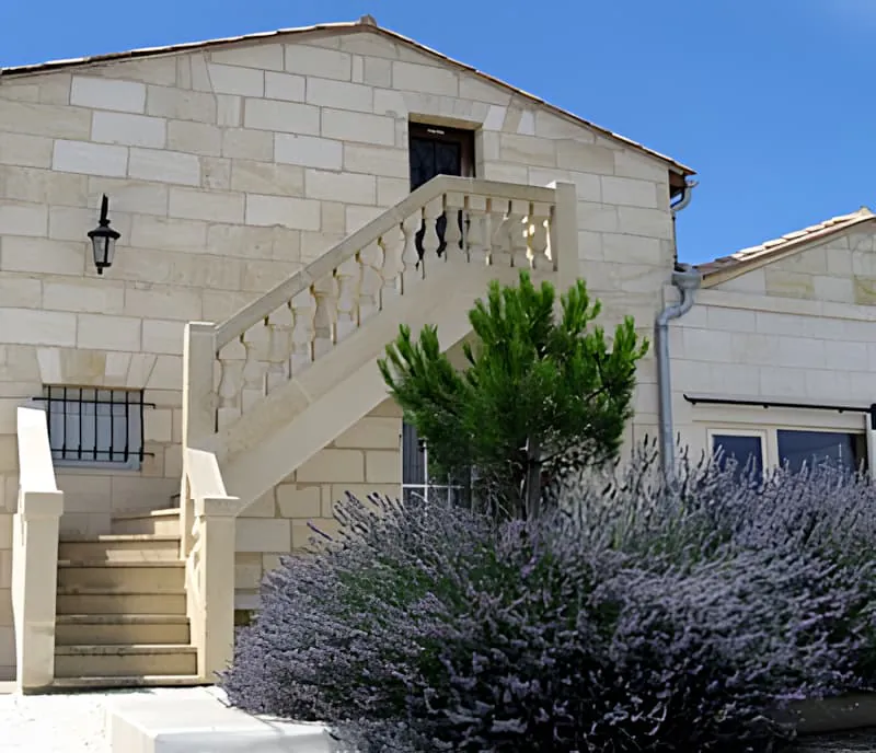 Stone steps leading up to a building, flanked by blooming purple lavender plants creating a fragrant pathway.