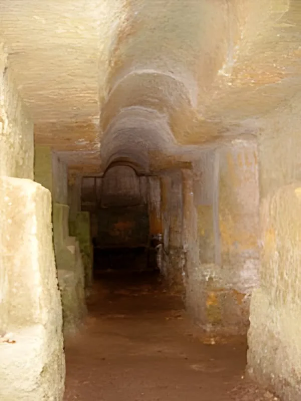 A carved limestone tunnel or corridor showing the warm ochre-colored walls and arched ceiling, representing ancient underground architecture.