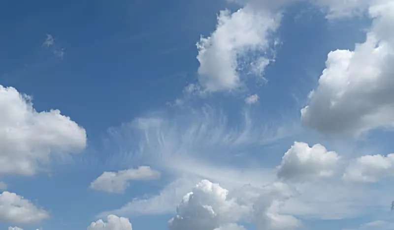 Un ciel bleu vif rempli de nuages blancs moelleux, représentant des conditions météorologiques idéales pour le travail du vignoble.
